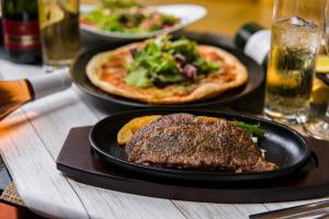 two plates of food on a table with pizza at Nagasaki Chapel Coconuts Hotel ＆Resort in Isahaya