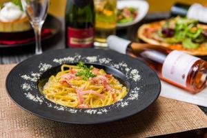 a plate of pasta with bacon on a table at Nagasaki Chapel Coconuts Hotel ＆Resort in Isahaya