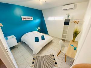 um quarto com uma parede azul e uma cama branca em spacieux T5, terrasse, proche centre,parking privé em Perpignan