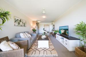ein Wohnzimmer mit Sofa und Fernseher in der Unterkunft Waterlily - One Bedroom Apartment in Airlie Beach