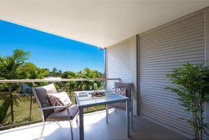 einen Balkon mit einem Glastisch und Stühlen in der Unterkunft Waterlily - One Bedroom Apartment in Airlie Beach