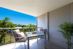 a balcony with a glass table and chairs on at Waterlily - Two Bedroom Apartment in Airlie Beach