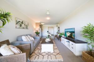 a living room with a couch and a tv at Waterlily - Two Bedroom Apartment in Airlie Beach