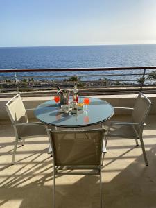 uma mesa e cadeiras numa varanda com o oceano em Anfi del Mar em La Playa de Arguineguín