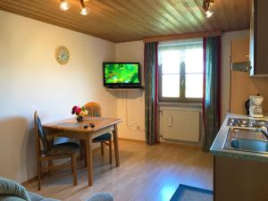a kitchen with a table and a tv on the wall at Mesnerhof in Bayerbach