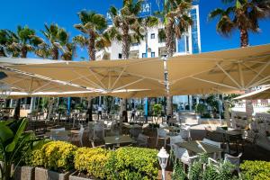 ein Restaurant mit Tischen und Stühlen unter Sonnenschirmen in der Unterkunft Iliria Internacional Hotel in Durrës