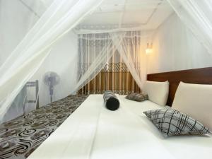 a bedroom with a large white bed with curtains at Nature Village Inn in Ella