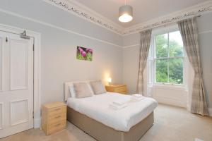 a white bedroom with a bed and a window at Home by The Meadows, close to City Centre in Edinburgh