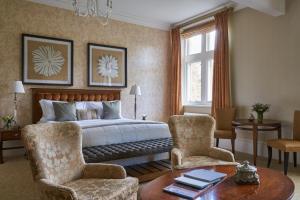 a bedroom with a bed and two chairs and a table at Rockliffe Hall Hotel Golf & Spa in Darlington