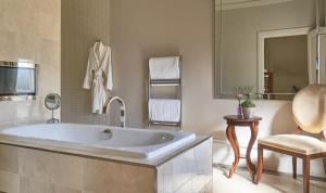 a bathroom with a large tub and a chair at Rockliffe Hall Hotel Golf & Spa in Darlington
