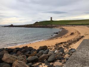 a beach with rocks and a lighthouse in the distance at The Royal Hotel in Anstruther