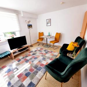a living room with a couch and chairs and a tv at Ferienwohnung am Rennsteig bei Eisenach - Ilona Schmidt in Wolfsburg-Unkeroda