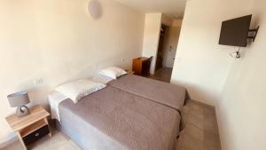 - une petite chambre avec un lit et une télévision dans l'établissement Hotel de la Poste, à Peymeinade