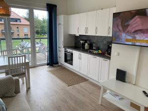 eine Küche mit weißen Schränken und ein Wohnzimmer in der Unterkunft Wohnen am Südstrand - Ferienwohnung 1 6 in Wyk auf Föhr