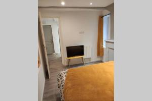 a bedroom with a bed and a flat screen tv at Appartement en plein centre ville d'Argentan in Argentan