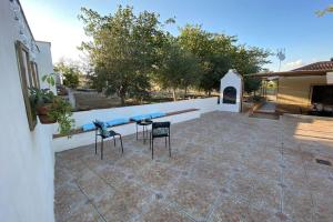 um pátio com duas cadeiras e uma mesa em frente a um edifício em Casa Cactus Preciosa casa rural con piscina y exterior privado muy amplio em Granada