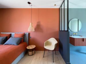 a bedroom with orange walls and a bed and a mirror at Les Loges en Provence - Villa Contemporelle in Pujaut +58 photos