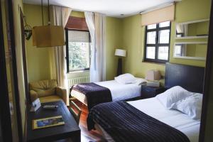 um quarto de hotel com duas camas e uma cadeira em Hotel Casa El Rapido em Felechosa