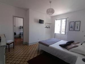 a white bedroom with a bed and a window at Hostel Rossio Alcobaça in Alcobaça
