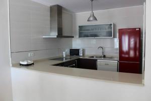 cocina con fregadero y nevera roja en Bonito apartamento en primera línea de campo de golf y vistas al mar en Mojácar