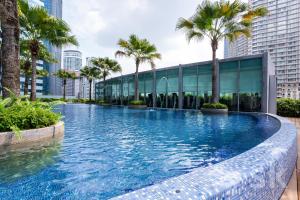 a swimming pool with palm trees and a building at Vortex suites klcc by Sofia in Kuala Lumpur
