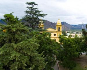a yellow building with a tower in the middle of trees at Altos Valles del Sol in Cafayate
