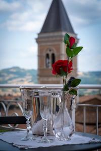 eine Rose in einer Vase auf einem Tisch mit Brille in der Unterkunft Residenza Le Terrazze di Gualdo Rent Rooms in Gualdo Tadino