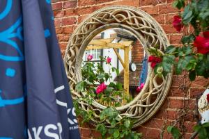 un miroir sur un mur de briques avec des fleurs. dans l'établissement The Coachmakers Arms, à Wallingford