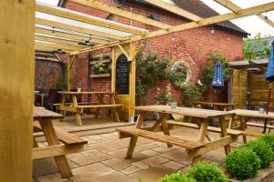 a patio with wooden picnic tables in front of a brick building at The Coachmakers Arms in Wallingford