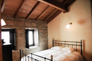 a bedroom with a bed in a room with a stone wall at Casa dos Limos Verdes in Folgosinho