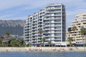 a large building on a beach with people on the beach at Apartamentos Hipocampos Calpe Rent Apart in Calpe