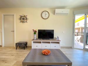 ein Wohnzimmer mit einem TV und einer Uhr an der Wand in der Unterkunft Modern 1 Bedroom Seaside Apartment with Pool in Fuengirola