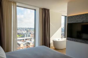 a bedroom with a tub and a large window at INNSiDE by Meliá Liverpool in Liverpool