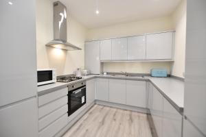 a white kitchen with white cabinets and a microwave at Sunny Shores Cottage in Troon