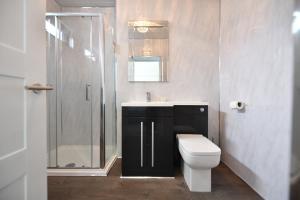 a bathroom with a toilet and a sink and a shower at Sunny Shores Cottage in Troon