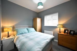a bedroom with a bed with two night stands and two lamps at Sunny Shores Cottage in Troon