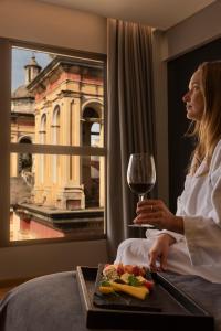 a woman sitting in a hotel room with a glass of wine at Windsor Hotel in Córdoba