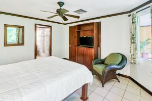 ein Schlafzimmer mit einem Bett, einem Stuhl und einem TV in der Unterkunft Pueblo Real Resort in Quepos