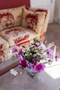 a vase filled with flowers on a table with a couch at Abbotshill, Dalvey Estate in Forres