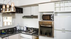 een keuken met een magnetron en een fornuis top oven bij Playa Gaviota Suites Apart in Las Gaviotas