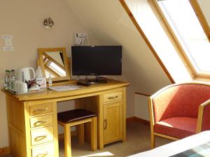 uma secretária com uma televisão e uma cadeira num quarto em The Sands Hotel, Orkney em Burray Village