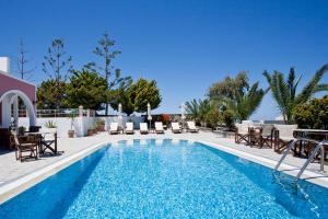a swimming pool with chairs and a table and a pool at Villa Koronios in Fira