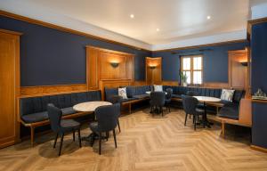 a waiting room with blue walls and tables and chairs at Maison Viktoria Augsburg in Augsburg