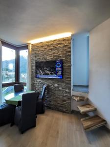 - un salon avec une table et un mur en pierre dans l'établissement Flamma Apartment - Ski in & Ski Out, à Breuil-Cervinia