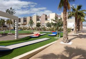 a building with palm trees and someogie boards on the grass at Fantastic apartment in Torrevieja