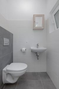 a white bathroom with a toilet and a sink at Baltic Center Bungalows in Sarbinowo +16 photos