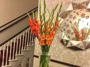 a vase with orange flowers on a table next to a staircase at Chaston Manor Hotel in Sandown