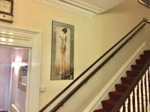 a staircase with a painting of a woman on the wall at Chaston Manor Hotel in Sandown