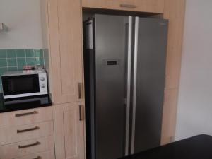 a stainless steel refrigerator in a kitchen with a microwave at Science Park Suite in Cambridge