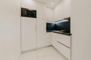 a kitchen with white cabinets and a microwave at Apartman Stari Toranj in Vukovar